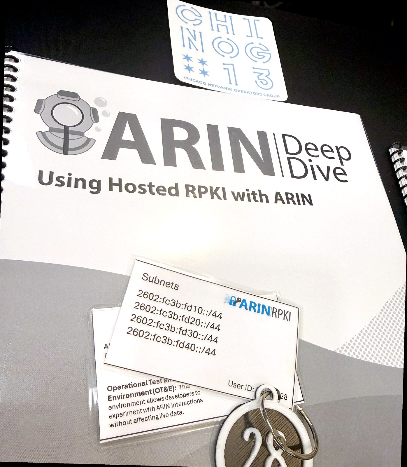 ARIN Deep Dive workbook for the hosted RPKI workshop at CHI-NOG 13, with OT&E credentials card and CHI-NOG 13 sticker